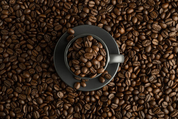 Cup with coffee beans in the center of the frame on coffee background. Flat lay