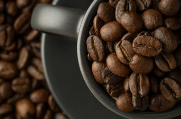 Cup and saucer with coffee beans on coffee background. Close-up, flat lay