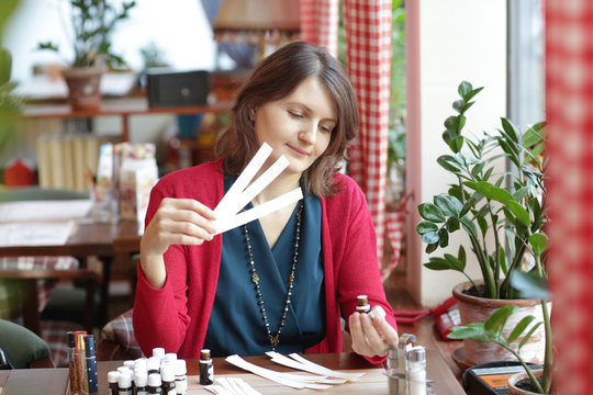 young woman in cafe with tea set smells perfumes with blotter close up photo