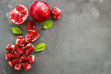 Ripe pomegranate fruit near leaf on grey background top-down copy space