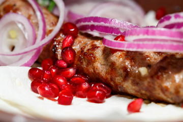 A dish cooked on the kebab grill. Georgian dishes. Garnished with onions and pomegranate seeds