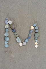 Fototapeta na wymiar alphabet by stone on the beach