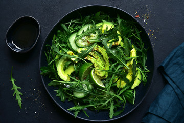 Green vegetable salad with arugula, cucumber and avocado. Top view with copy space.