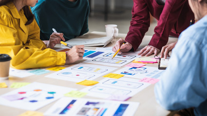 Close up ux developer and ui designer brainstorming about mobile app interface wireframe design on table with customer breif and color code at modern office.Creative digital development agency. - obrazy, fototapety, plakaty
