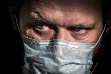 Sick old man with medical face mask portrait close up illustrates pandemic coronavirus disease on dark background. Covid-19 contamination concept.