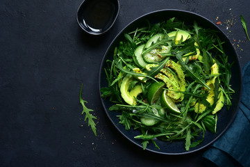 Green vegetable salad with arugula, cucumber and avocado. Top view with copy space.