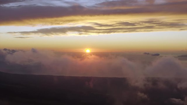Aerial, tracking, drone shot of sunset above clouds and the ocean, high above mountains on Maui island, in Hawaii, USA - HD crop