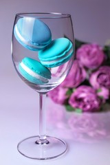 wine glass of blue macaroons on pinck flowers background