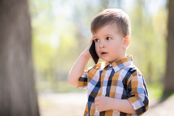 beautiful baby speaks on the phone in nature