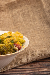 Vegetable salad in a white ceramic bowl on a rough cloth background. Close up.