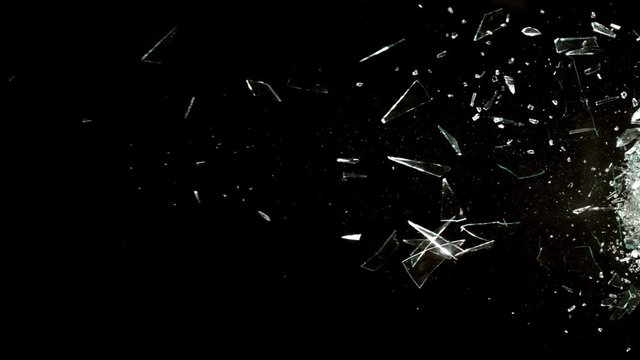 Profile view of Glass breaking in slow motion on black background