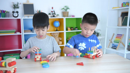 Fototapeta premium Educational concepts. A group of boys playing wooden toys in the classroom, With a bright smiley face.