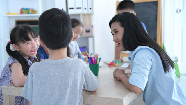 Educational concepts. The teacher is teaching kindergarten children to draw pictures in the classroom, With a bright smiley face.