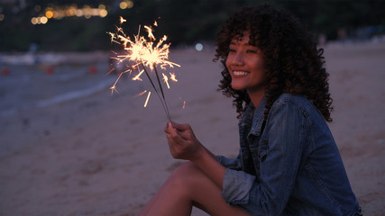 Holiday concept. A beautiful woman playing fireworks on the beach. 4k Resolution.