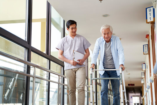 asian old man walking with a walker in rehab center guided by physical therapist