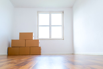 Umzugskartons in einer leeren Wohnung vor einer weißen Wand