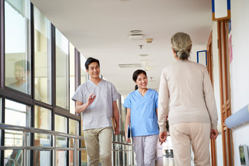 asian employee greeting residents in hallway of nursing home © imtmphoto