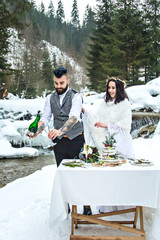 The bride and groom in the winter on the nature drink champagne, hug - 329764996