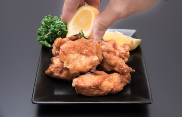 鶏の唐揚げにレモンをかける男性の手元