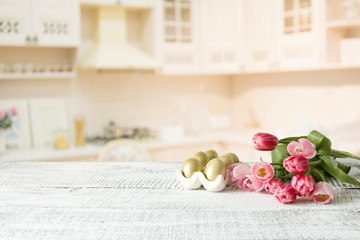 Easter eggs, tulips on kitchen white wooden table. Spring composition. Space for design.