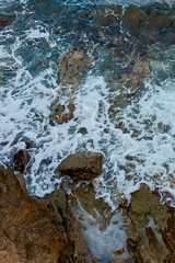 waves of the Mediterranean rush to the hot rocky beach on the Greek island of Crete