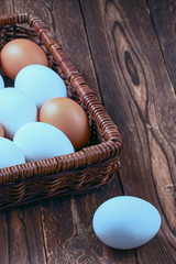 Fresh chicken eggs in a wicker basket on a dark wooden background. Healthy eating concept