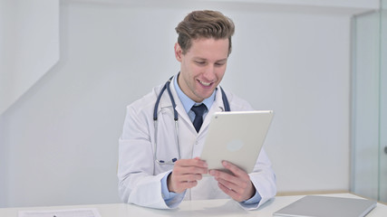Fototapeta premium Young Male Doctor Watching Video on Tablet in Clinic