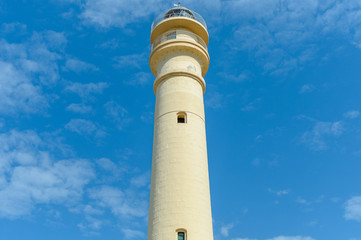 Faro blanco sobre cielo azul con nubes