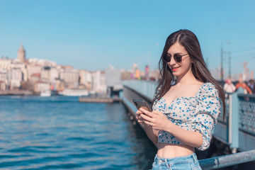 Fototapeta na wymiar Attractive young brunette woman looking to mobile phone with her sunglasses in Istanbul copy space