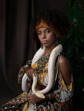 Noble portrait of a dark-skinned beauty in a traditional dress with an albino snake