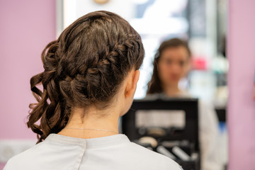 Details of the hairstyle of a young woman with braids, curls and flowers