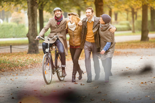 Freunde spazieren und radeln durch herbstlichen Stadtpark