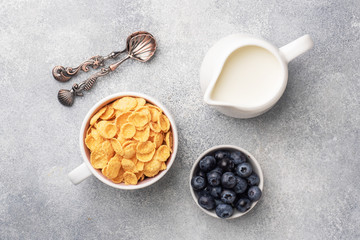 Obraz na płótnie Canvas Corn flakes made from natural cereals with fresh blueberries, honey and milk. The concept of a healthy wholesome Breakfast. copy space Grey concrete background