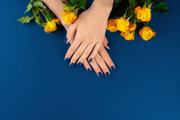 Obraz na płótnie Canvas Beautiful woman hands with manicure holding roses against classic blue background