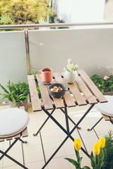 Breakfast on the wooden table - outdoor furniture on the balcony decorated with a lots of flower...