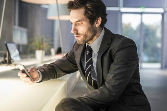 Businessmann am Handy an Theke