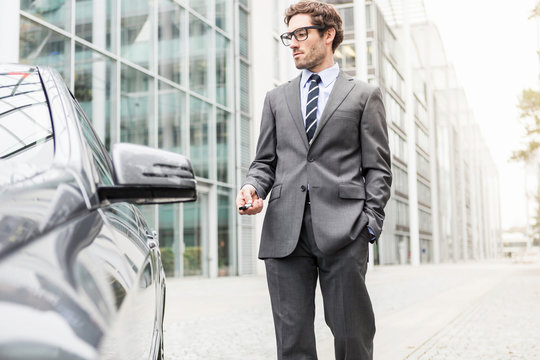 Businessmann mit Auto  in st&auml;dtischem Umfeld