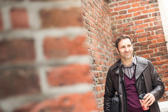 Mann in Lederjacke mit Cafe to Go im st&auml;dtiscxhen Umfeld