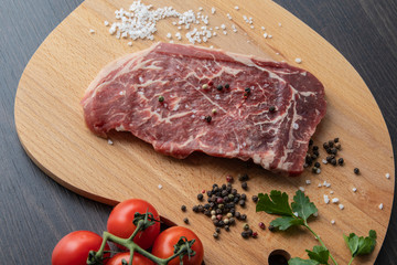 Raw beef steak with spices on a dark board. View from above.