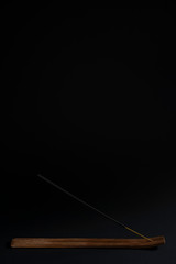 Aromatic stick in a stand on a black background. Spiritual smoke, strong smell for the ceremony. Natural aromatherapy, black background, isolated