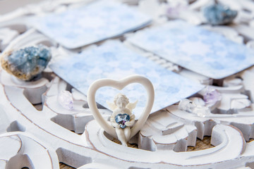 Deck with divination homemade Angel cards on bright white table, surrounded with semi precious...