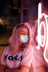 Coronavirus lovely blonde woman with glasses on the street with neon background
