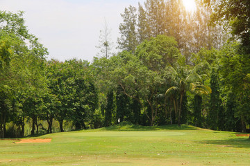 The evening golf course has sunlight shining down at golf course in Thailand