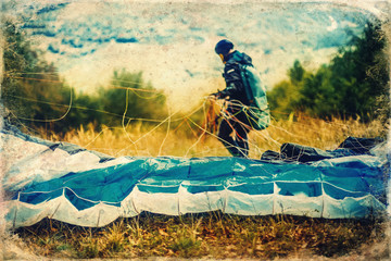 Fototapeta na wymiar Paragliding in the mountains, paraglider on the ground, old photo effect.