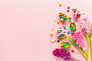 Chocolate Easter eggs and colorful candies on pastel pink paper background. flat lay, top view, overhead, copy space, template, mockup