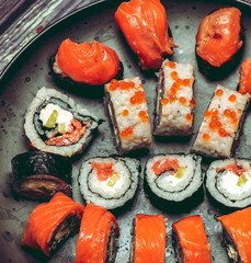 Various kinds of sushi served on dark plate macro