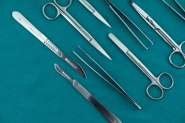 Basic surgical instrument scalpel forceps tweezers scissors spread on surgical green drape fabric