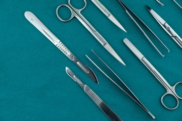 Basic surgical instrument scalpel forceps tweezers scissors spread on surgical green drape fabric