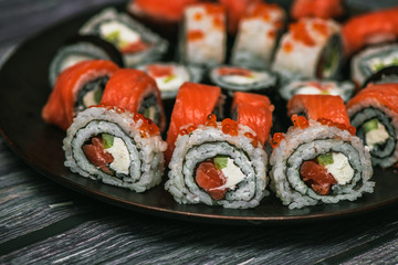 Various kinds of sushi served on dark plate macro