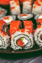 Various kinds of sushi served on dark plate macro